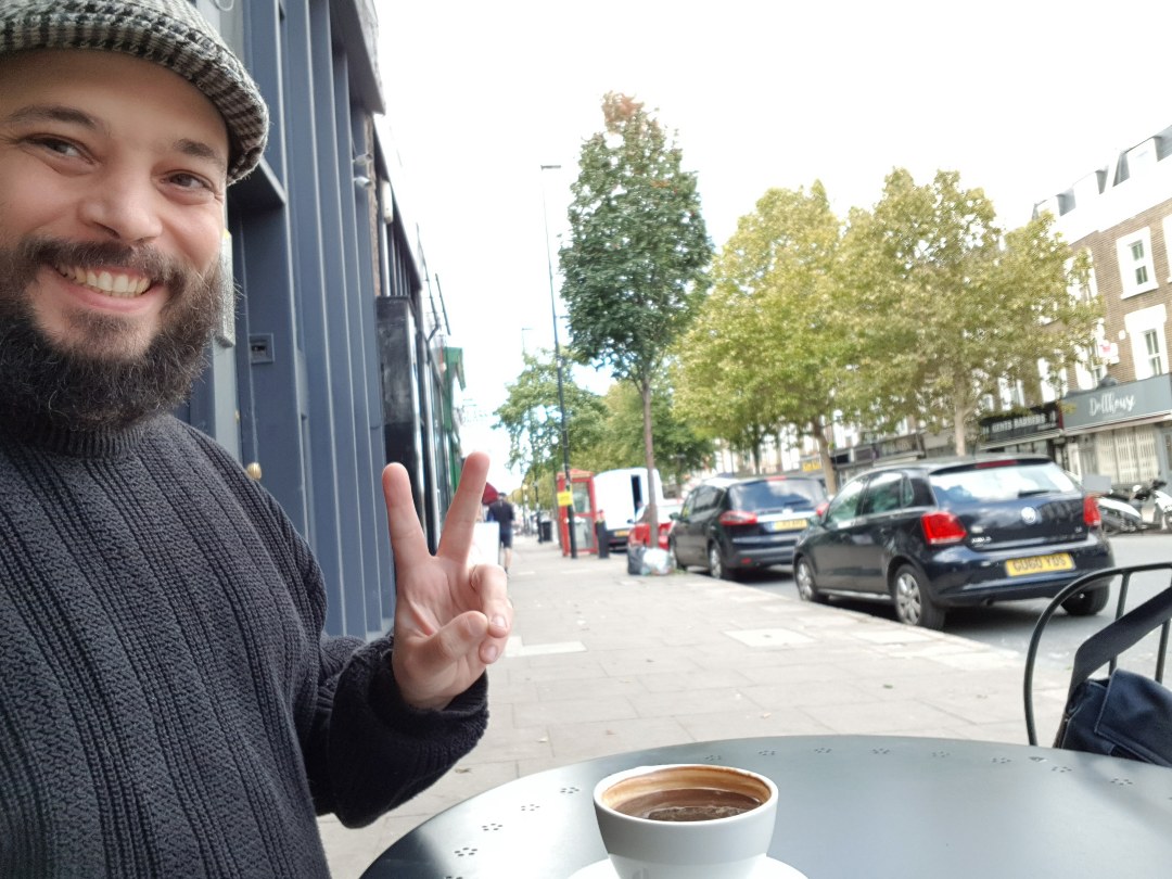 photo of me sitting at an outside table drinking coffee